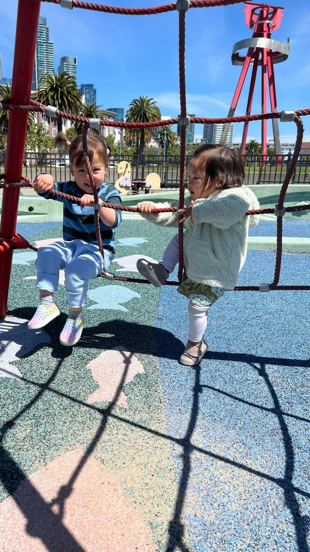 Two children climbing on a rope net at a playground