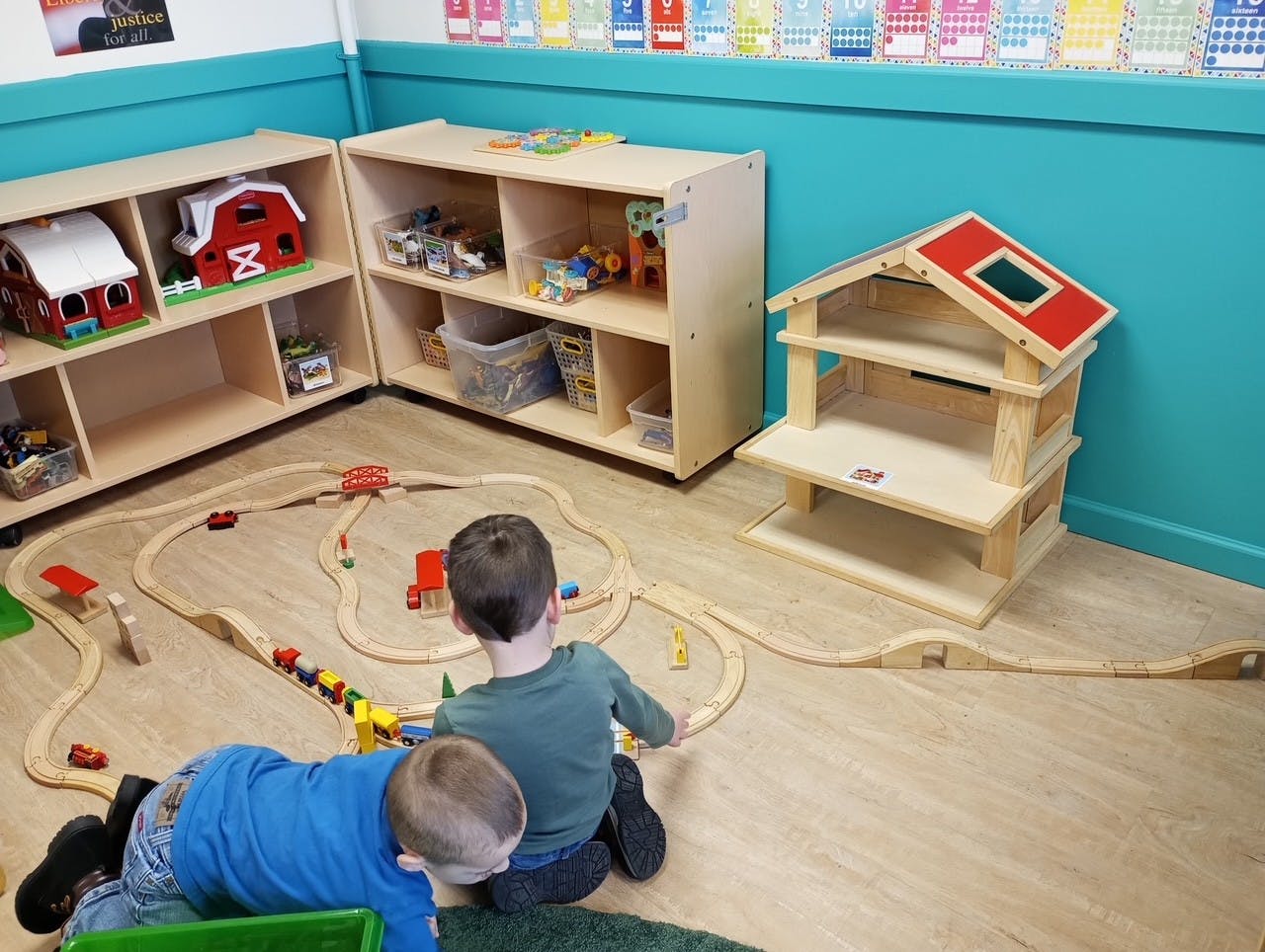 Two children playing with a wooden train set on the floor