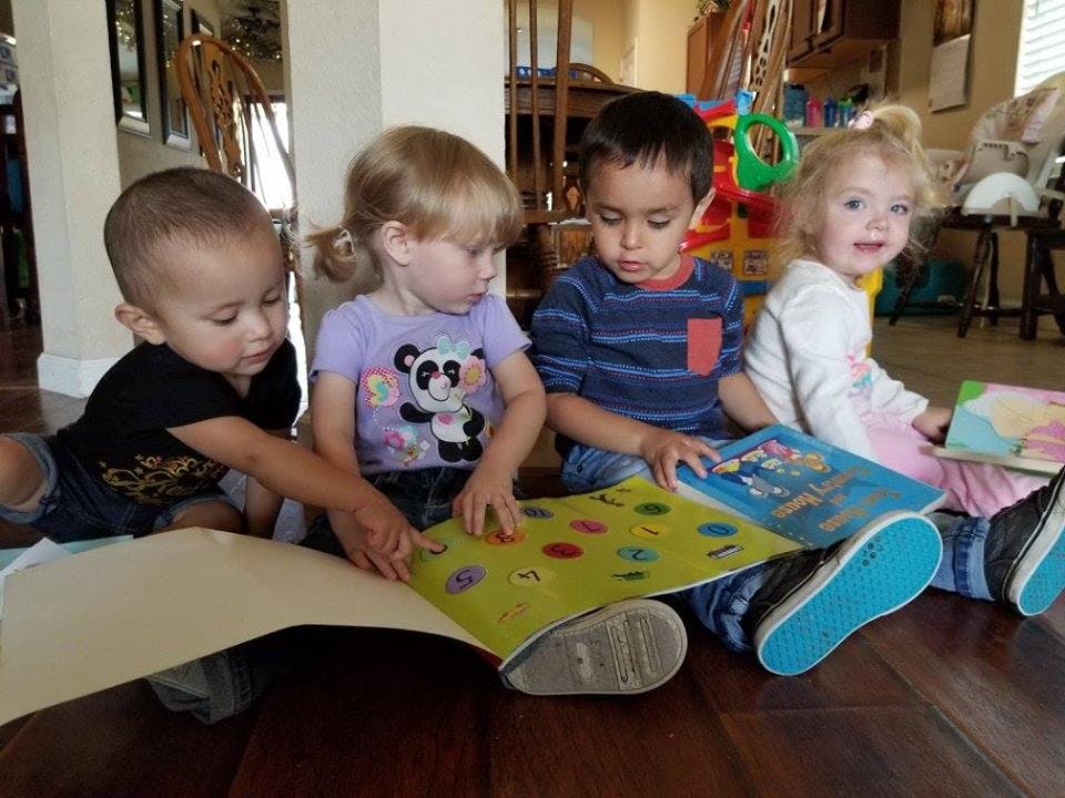 Four children sitting on the floor looking at books