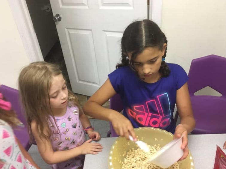 Two children mixing ingredients in a bowl