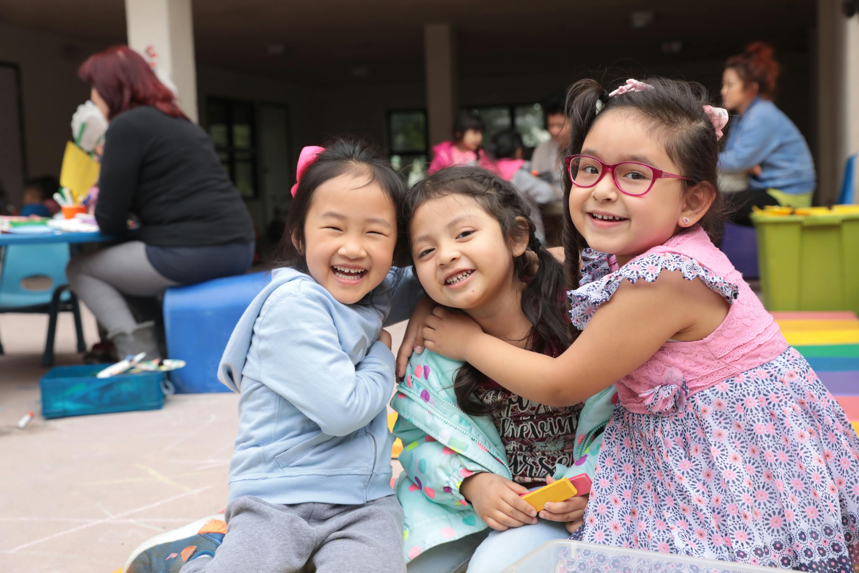 Three children smiling and embracing