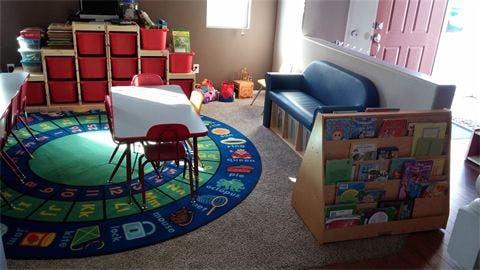 Children's play area with a rug, table, chairs, and storage