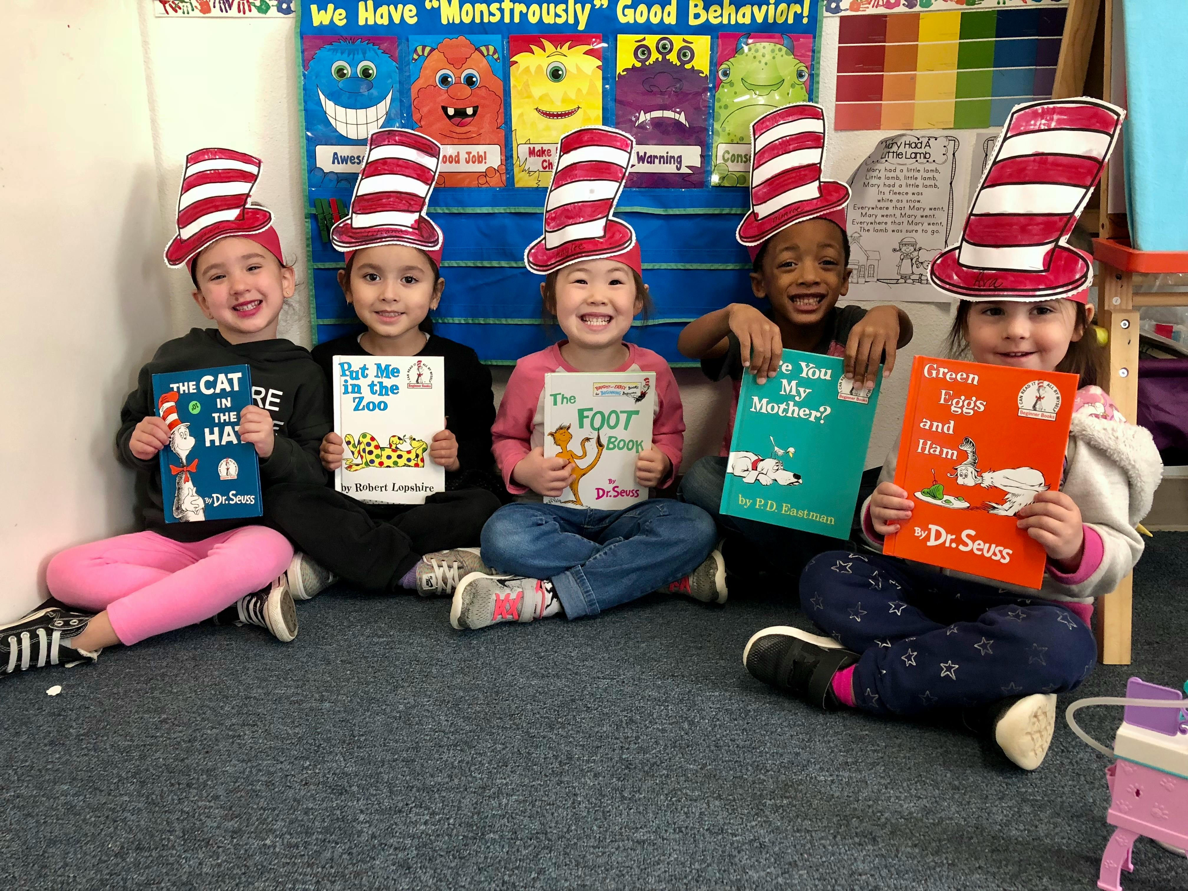 Five children wearing striped hats and holding books