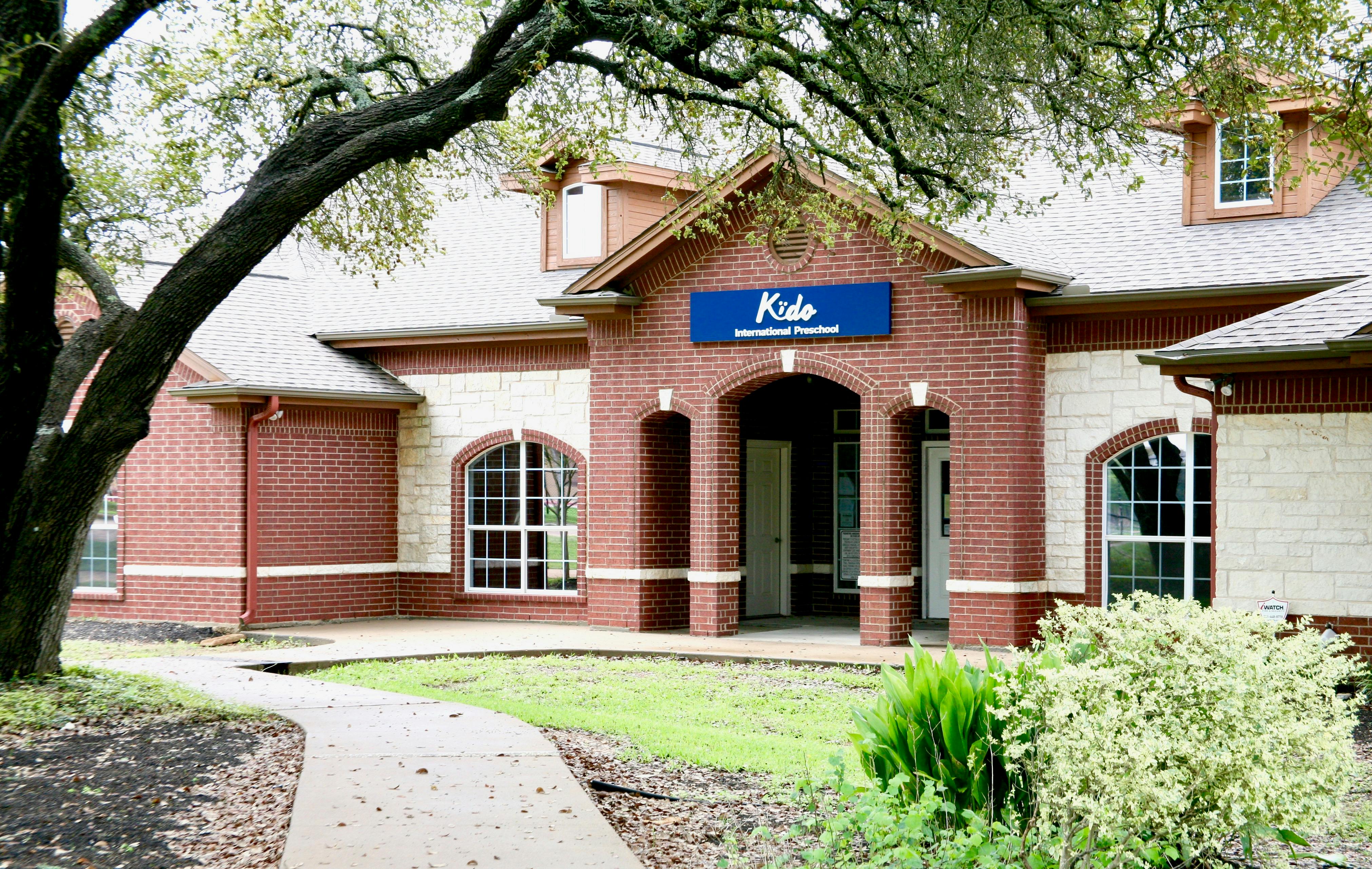 Building with brick facade and a blue sign that says "Kids"
