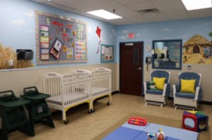 Infant room with cribs, high chairs, and rocking chairs