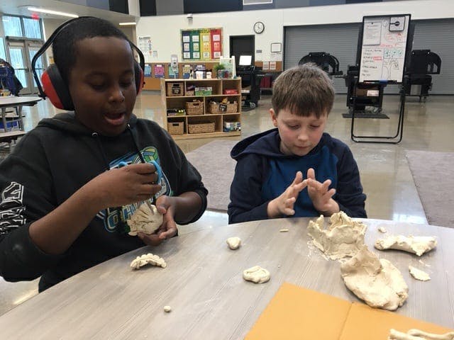 Two children working with clay at a table