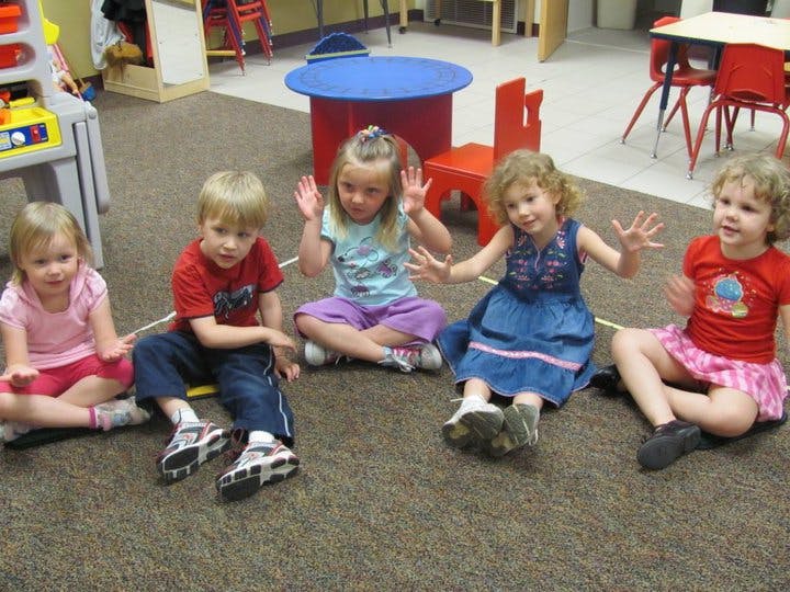 Five children sitting on the floor in a classroom