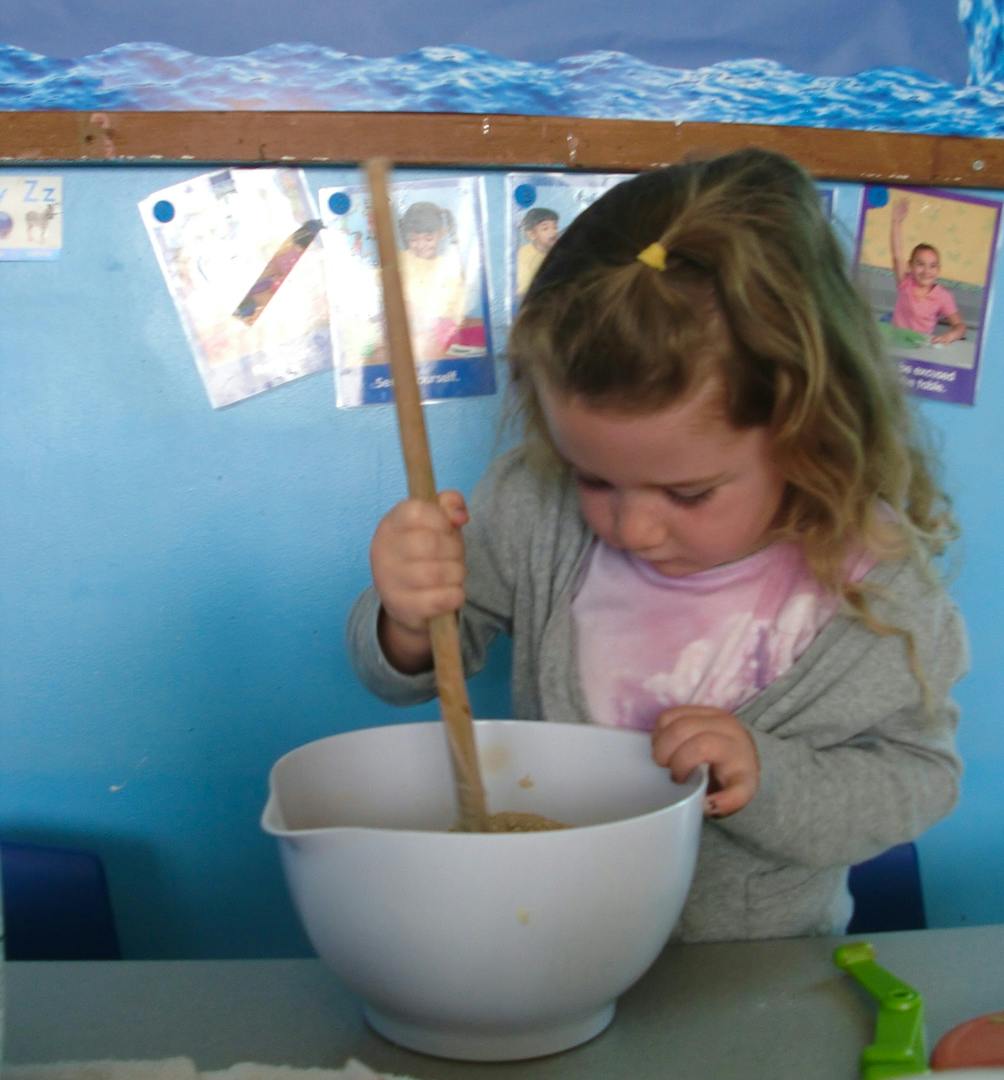 Child stirring a bowl with a wooden spoon