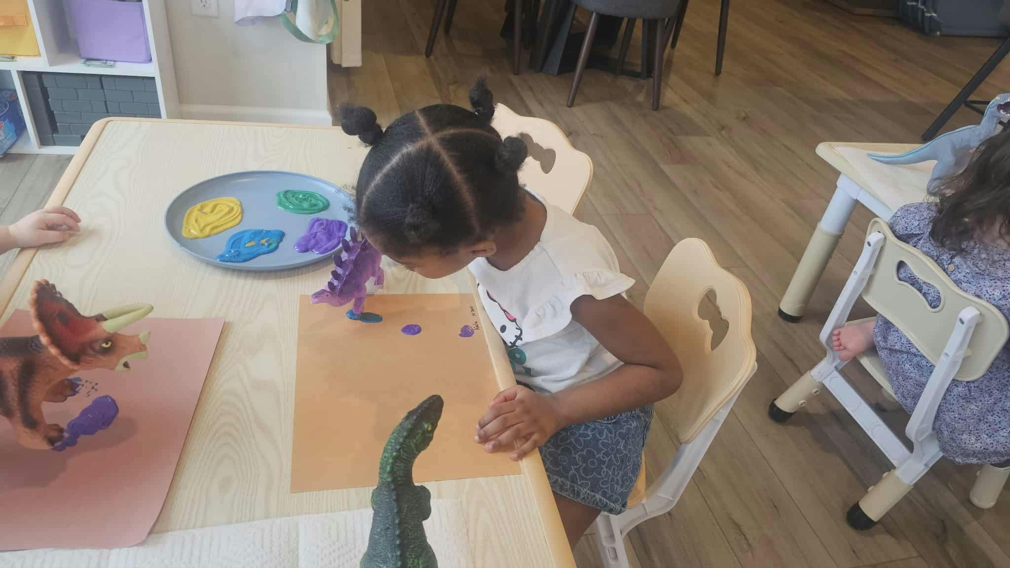 Child painting with dinosaur toys