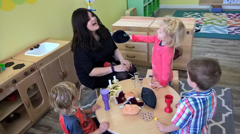 Adult and three children playing at a table