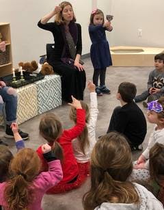 Adult and children in a classroom, one child holding a cup