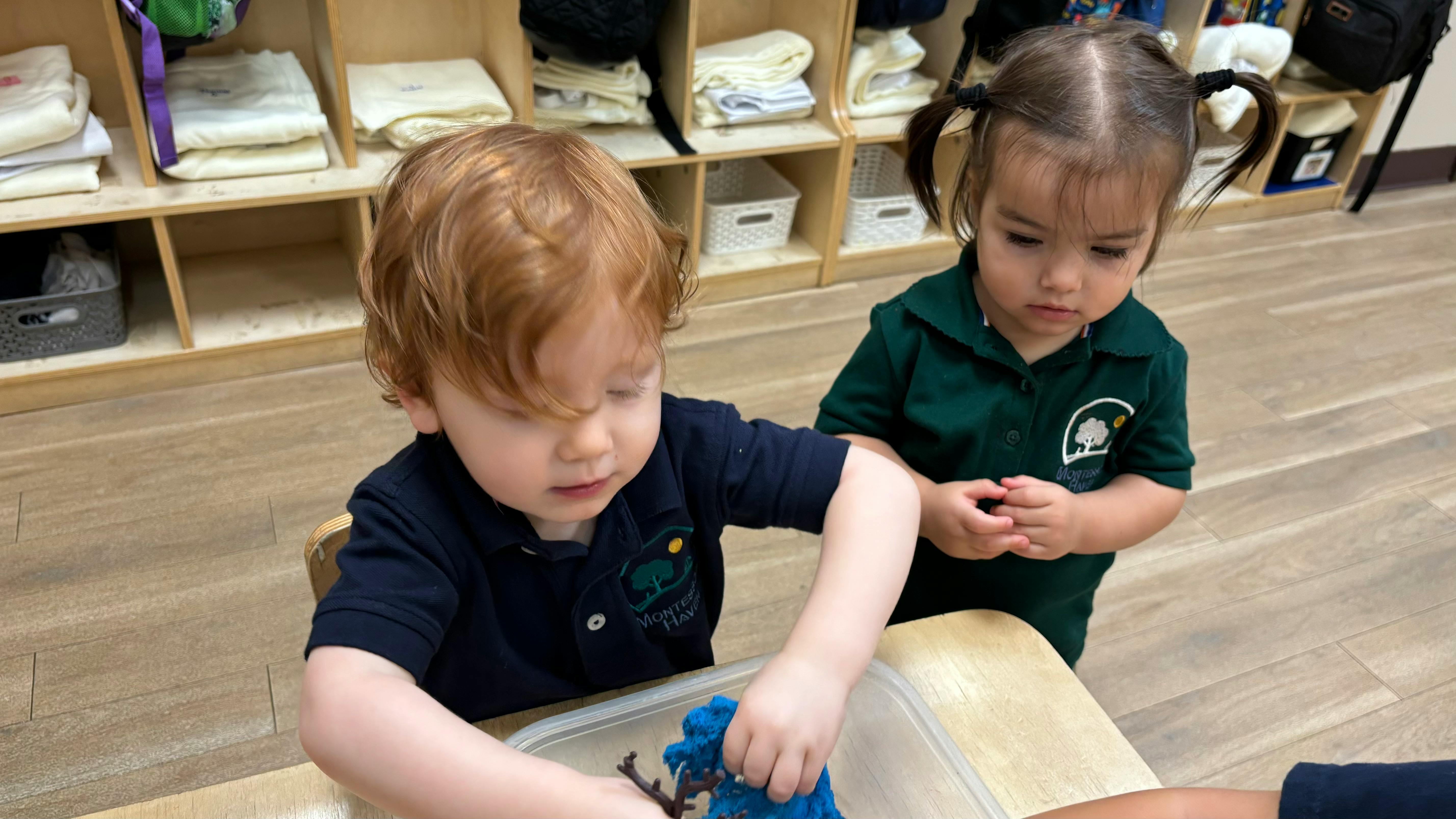 Two children playing with blue material in a classroom