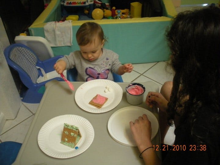 Child and person decorating gingerbread houses