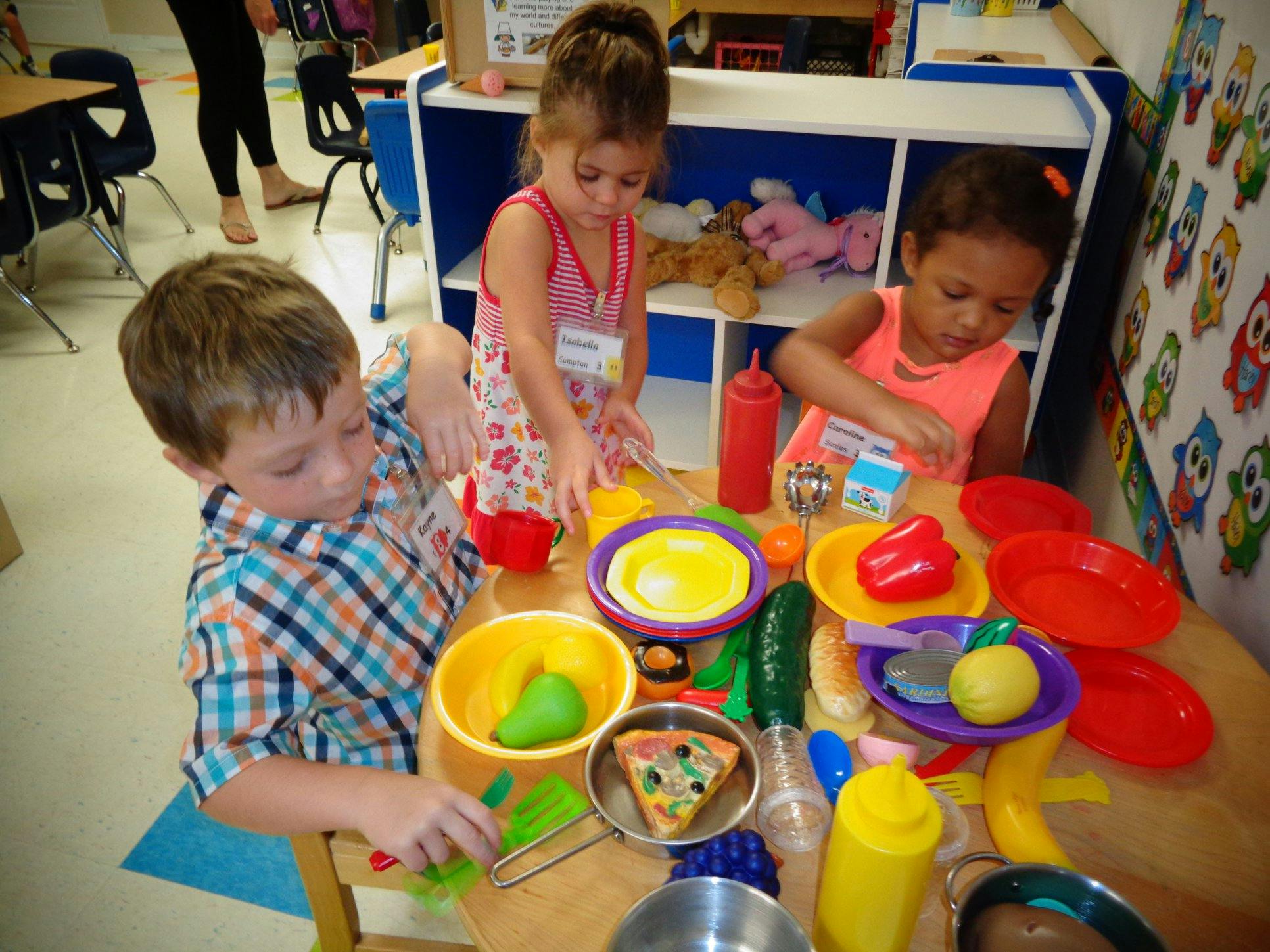 Three children playing with toy food at a table