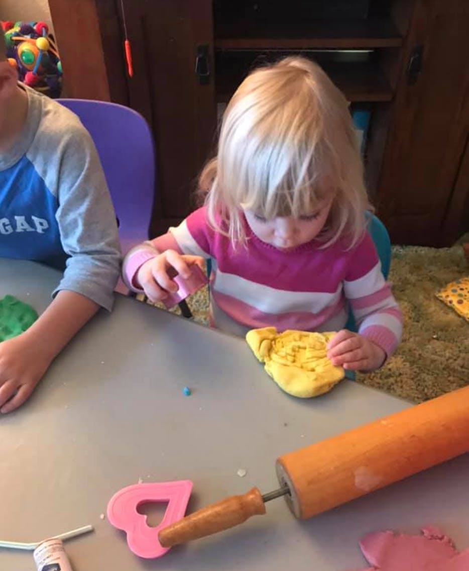 Child playing with yellow dough at a table