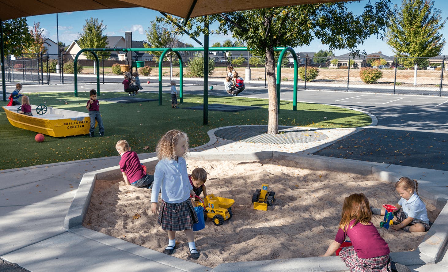 Children playing in a sandbox and on swings at a playground