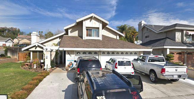 House with a driveway and multiple cars parked