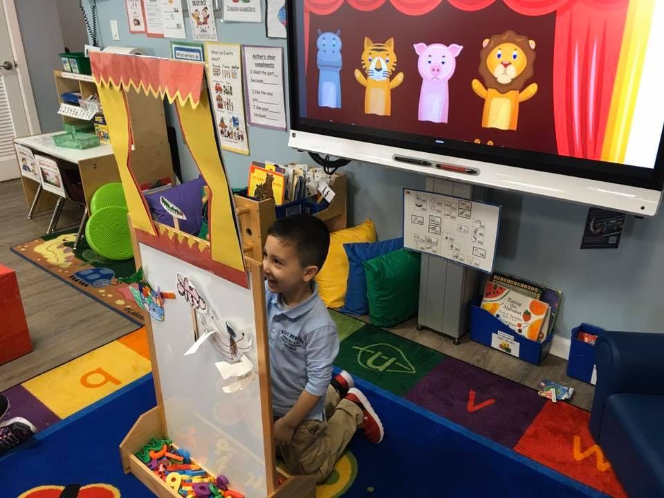 Child standing next to a puppet theater in a classroom