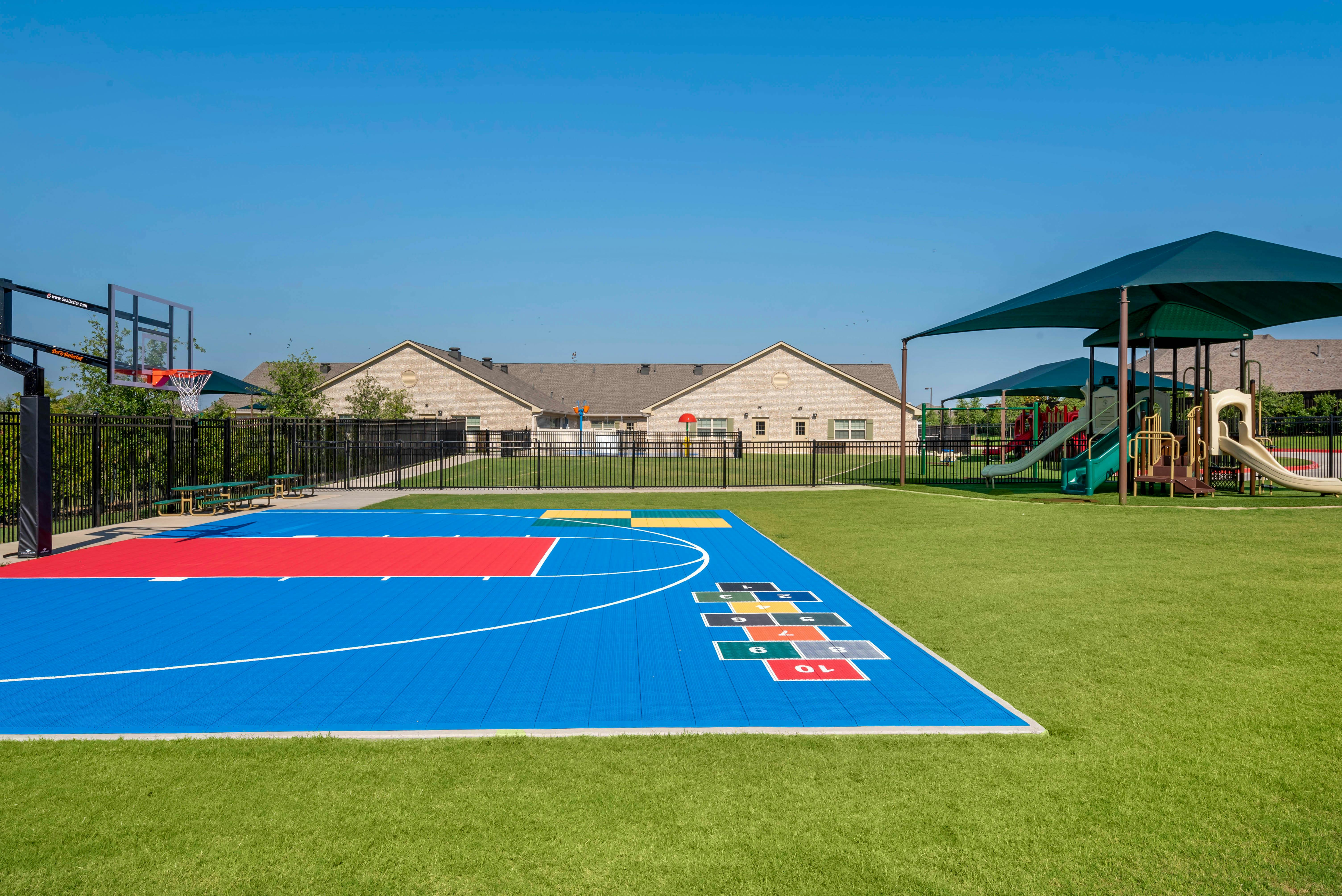 Basketball court and playground with a hopscotch grid and artificial turf