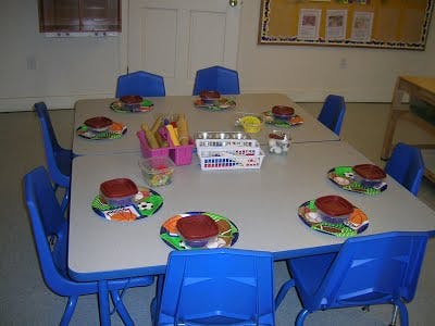 Classroom tables with blue chairs and place settings