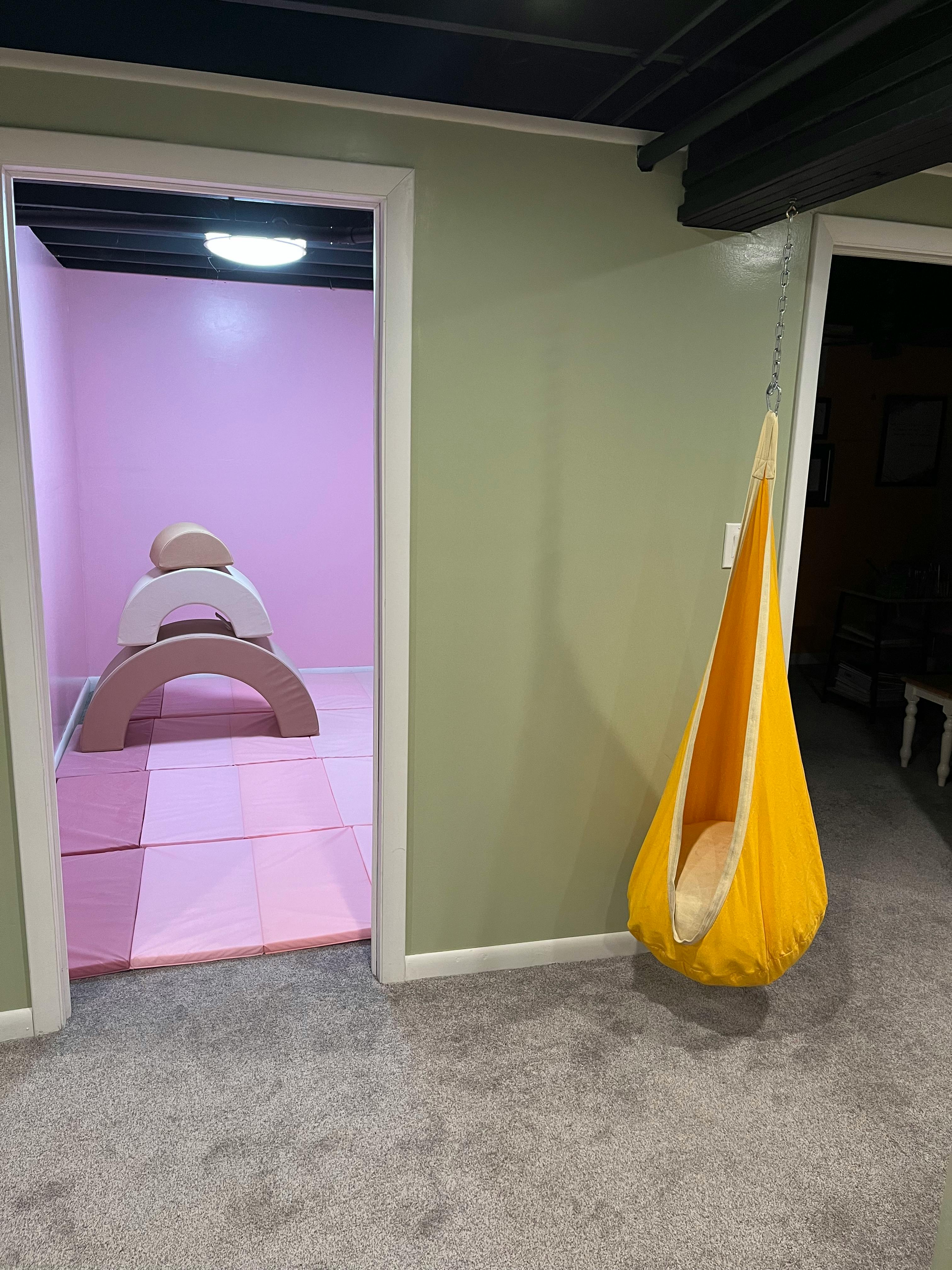 Playroom with soft play equipment and a hanging swing chair