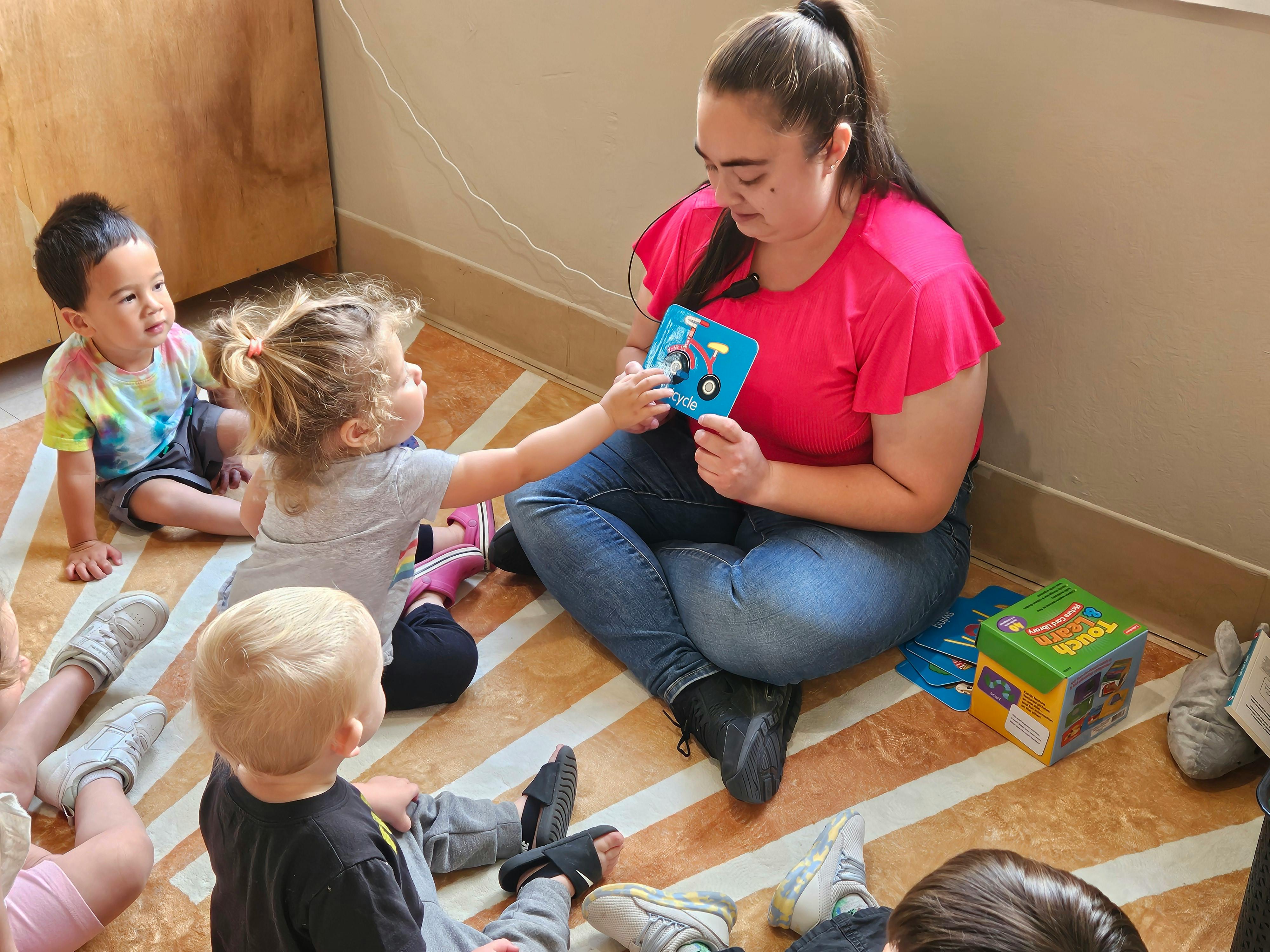 Adult showing a bicycle flashcard to a child in a classroom setting
