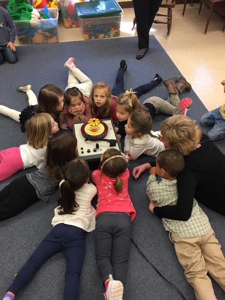 Children and an adult gathered around a record player on the floor