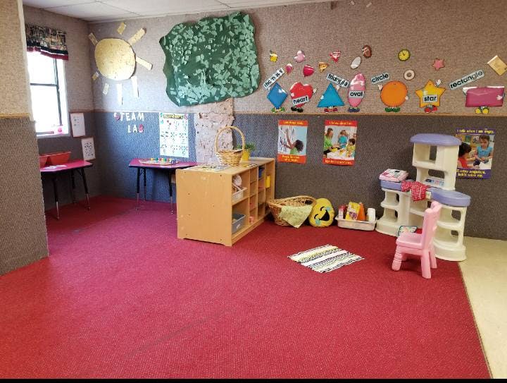 Classroom with red carpet, small tables, and children's furniture