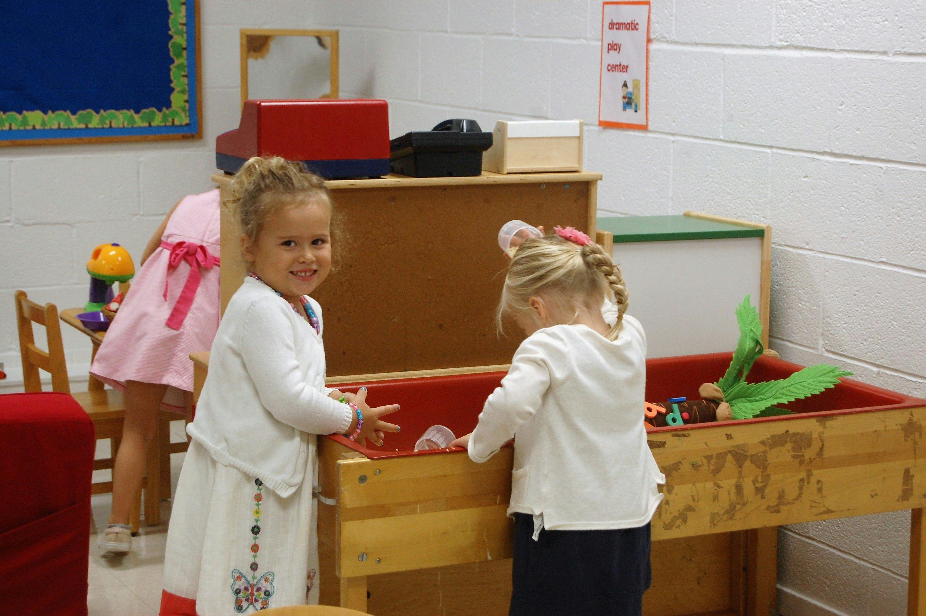 Two children playing at a sand and water table in a classroom