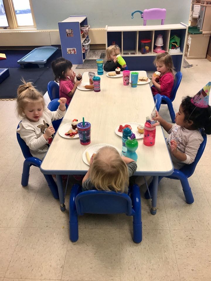 Children sitting at a table with plates and cups