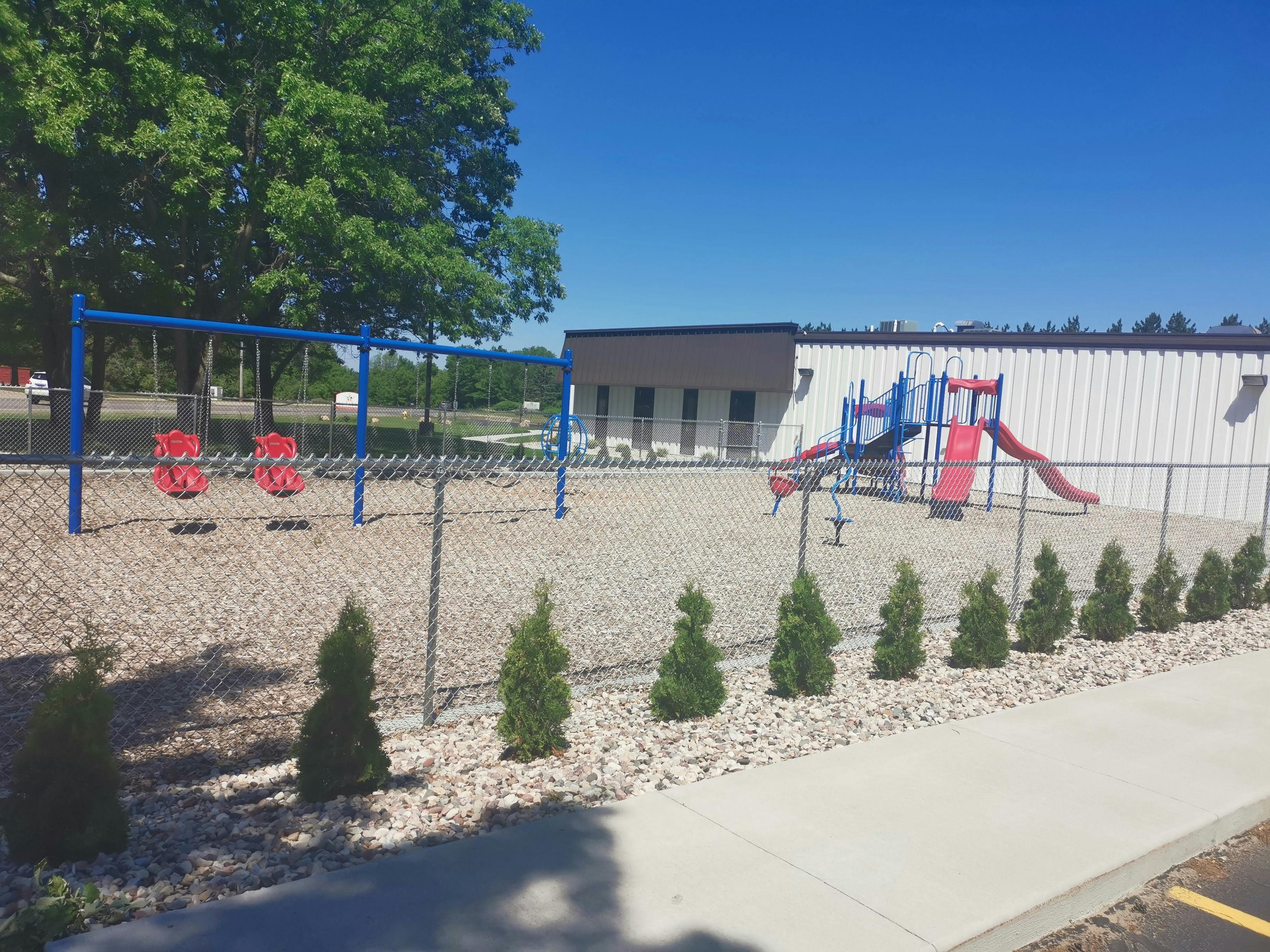 Playground with swings and slides behind a fence