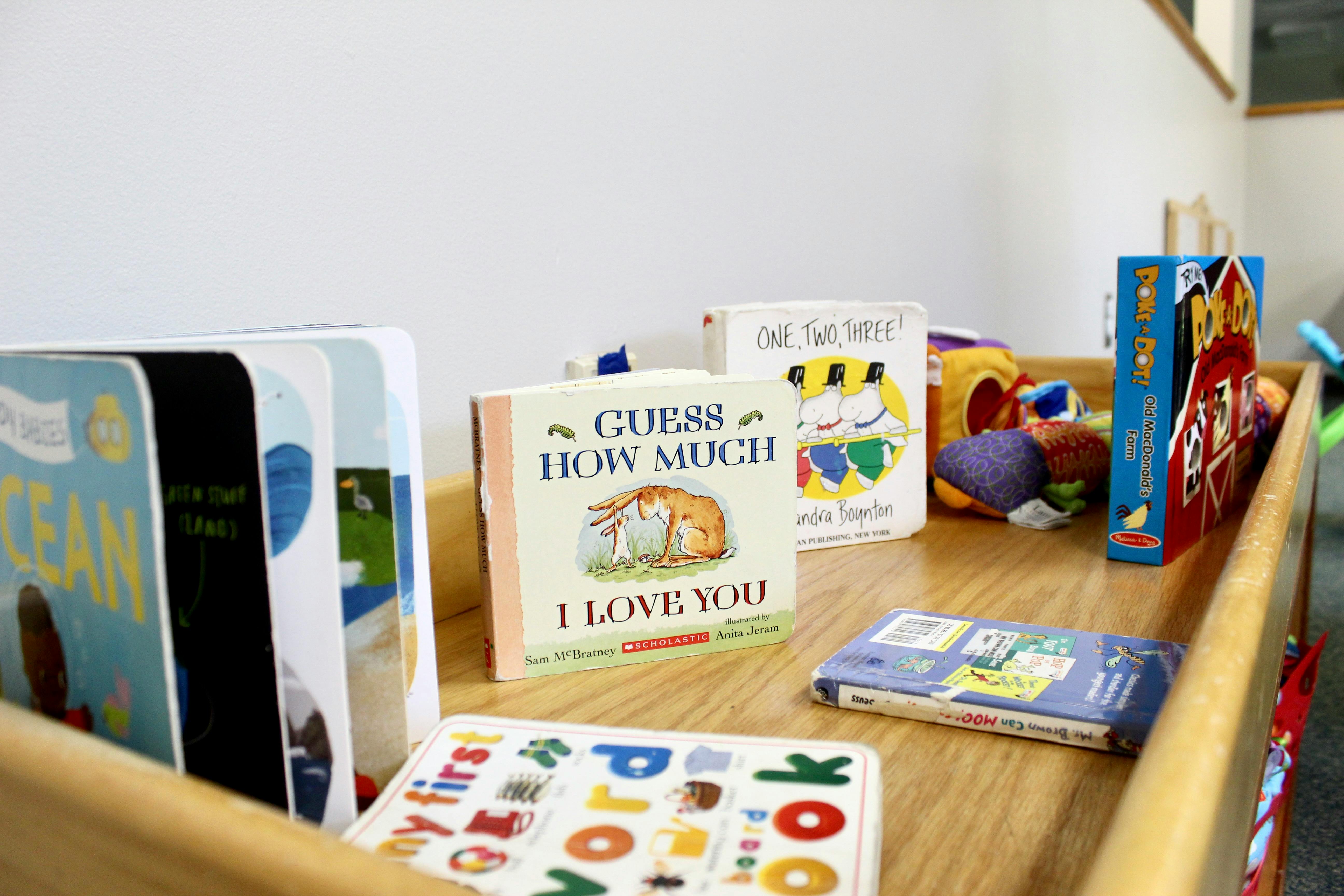 Children's books and toys on a wooden shelf