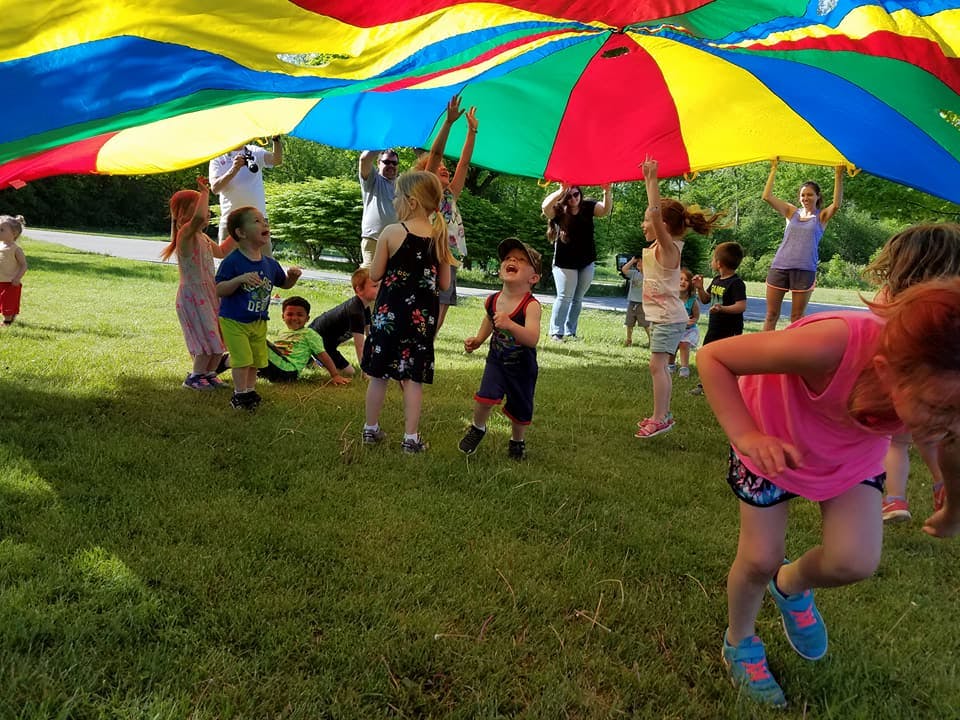 Children and adults playing with a colorful parachute outdoors