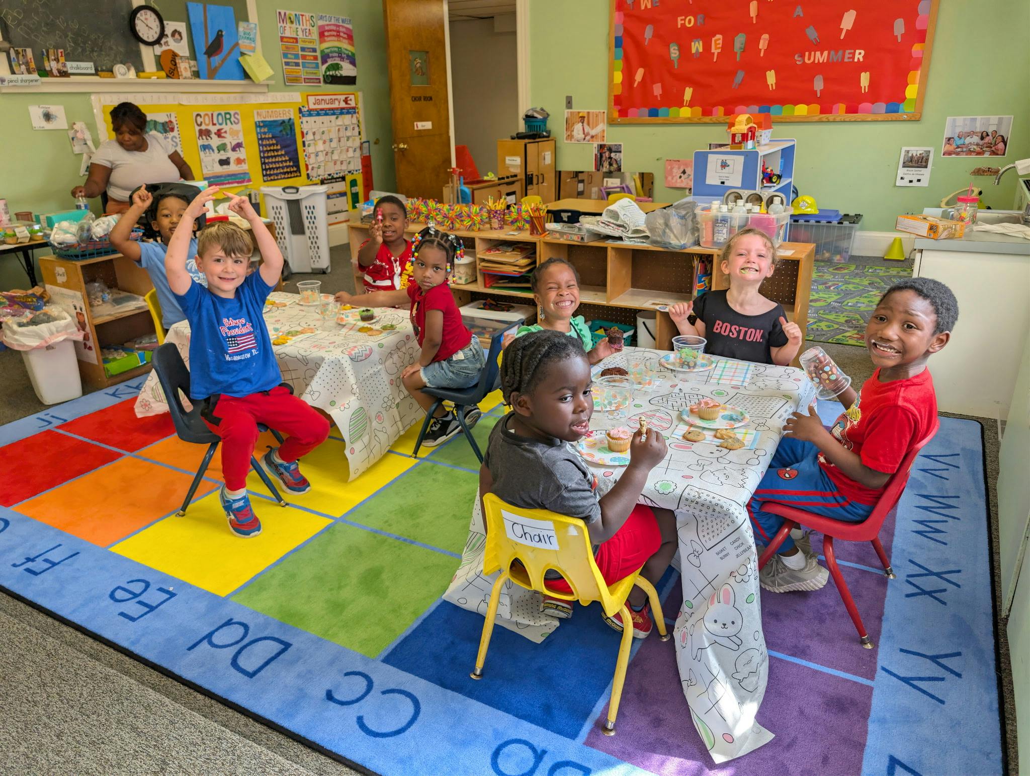 Group of children eating snacks at tables in a brightly decorated classroom