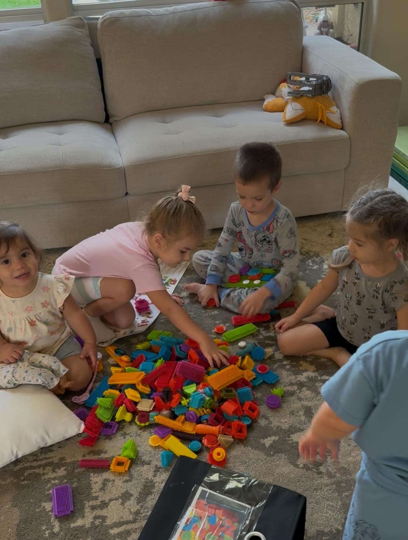 Several children playing on the floor with colorful building blocks