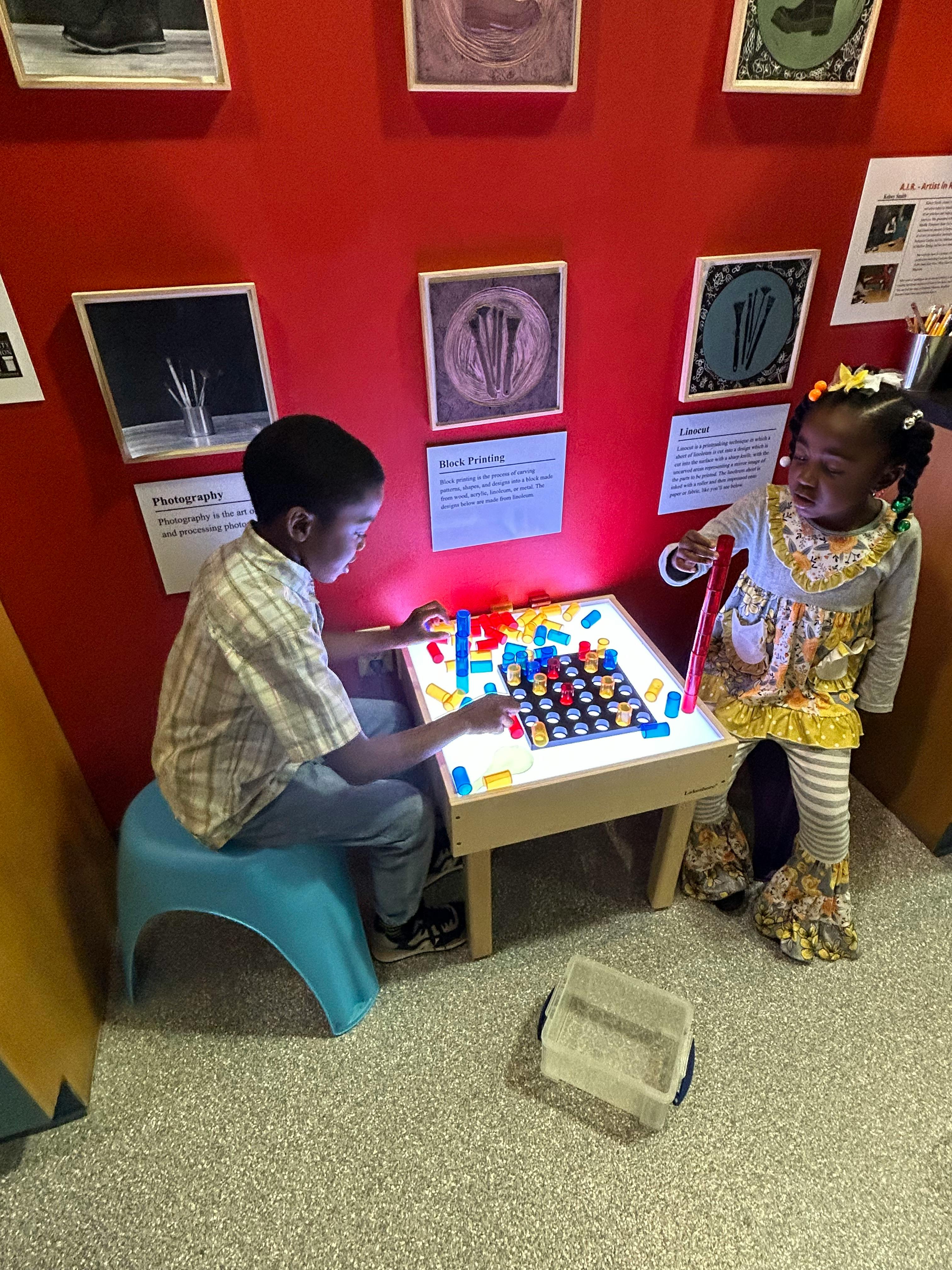 Two children playing with colorful blocks on a light table