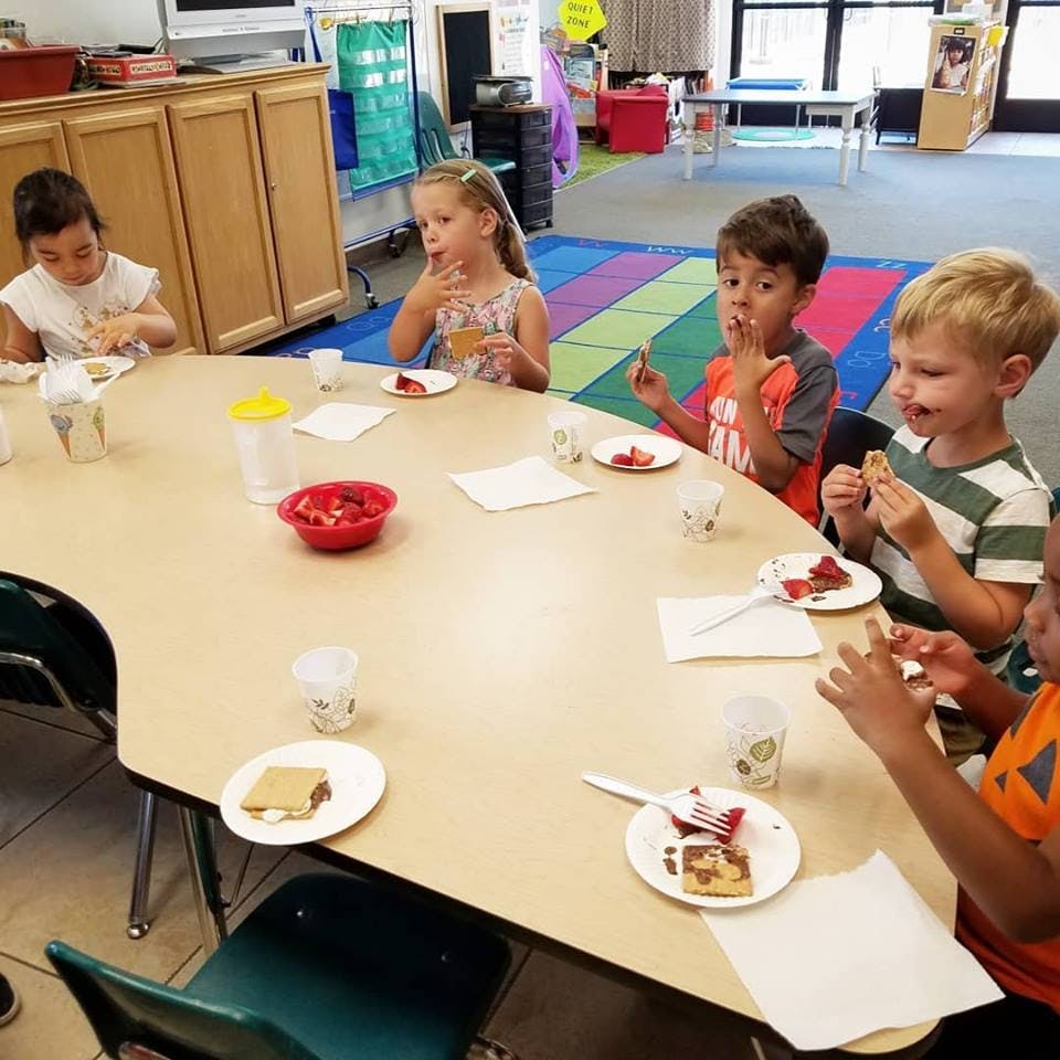 Children eating at a table in a classroom
