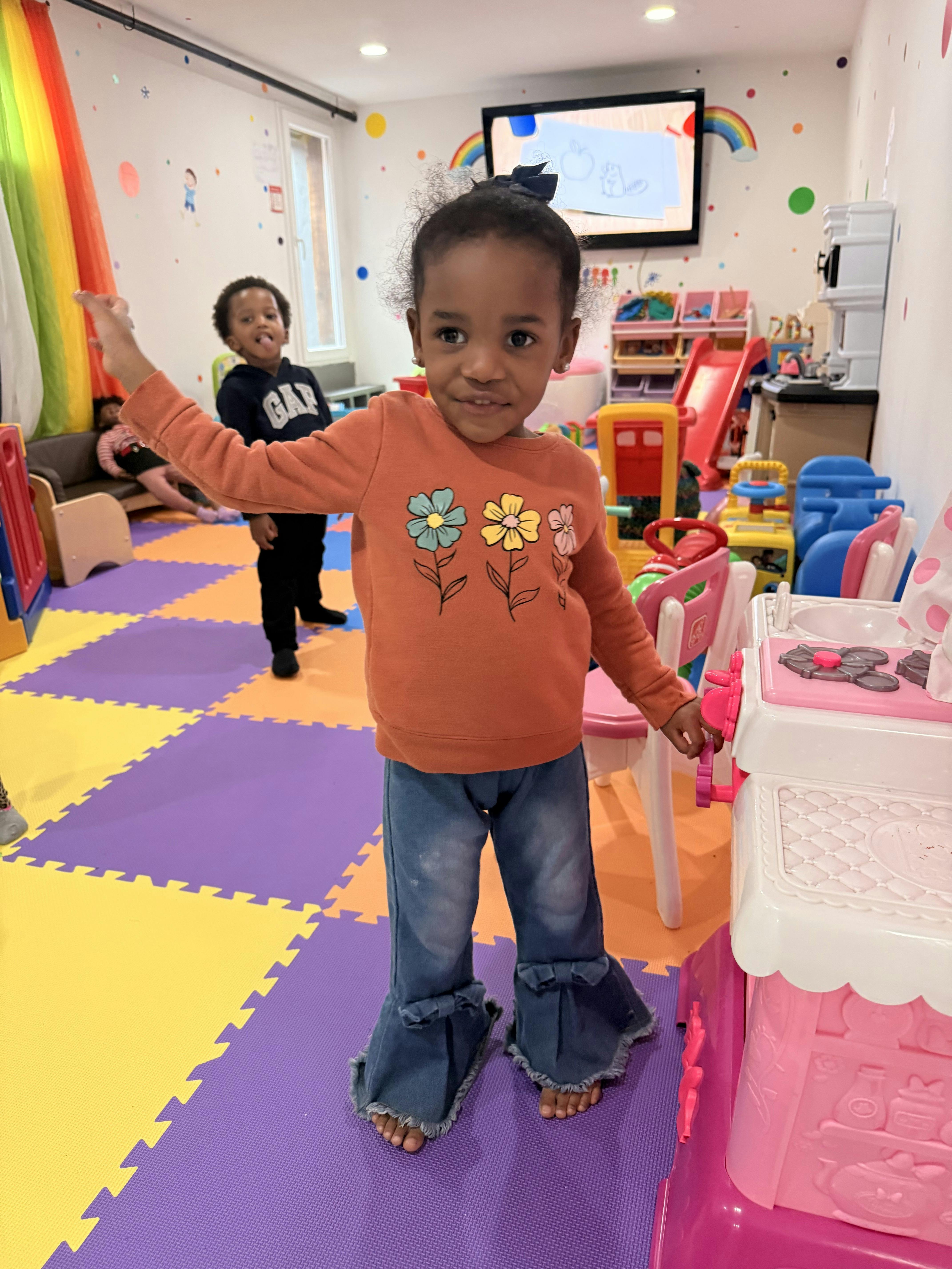 Child in a classroom reaching out with one arm