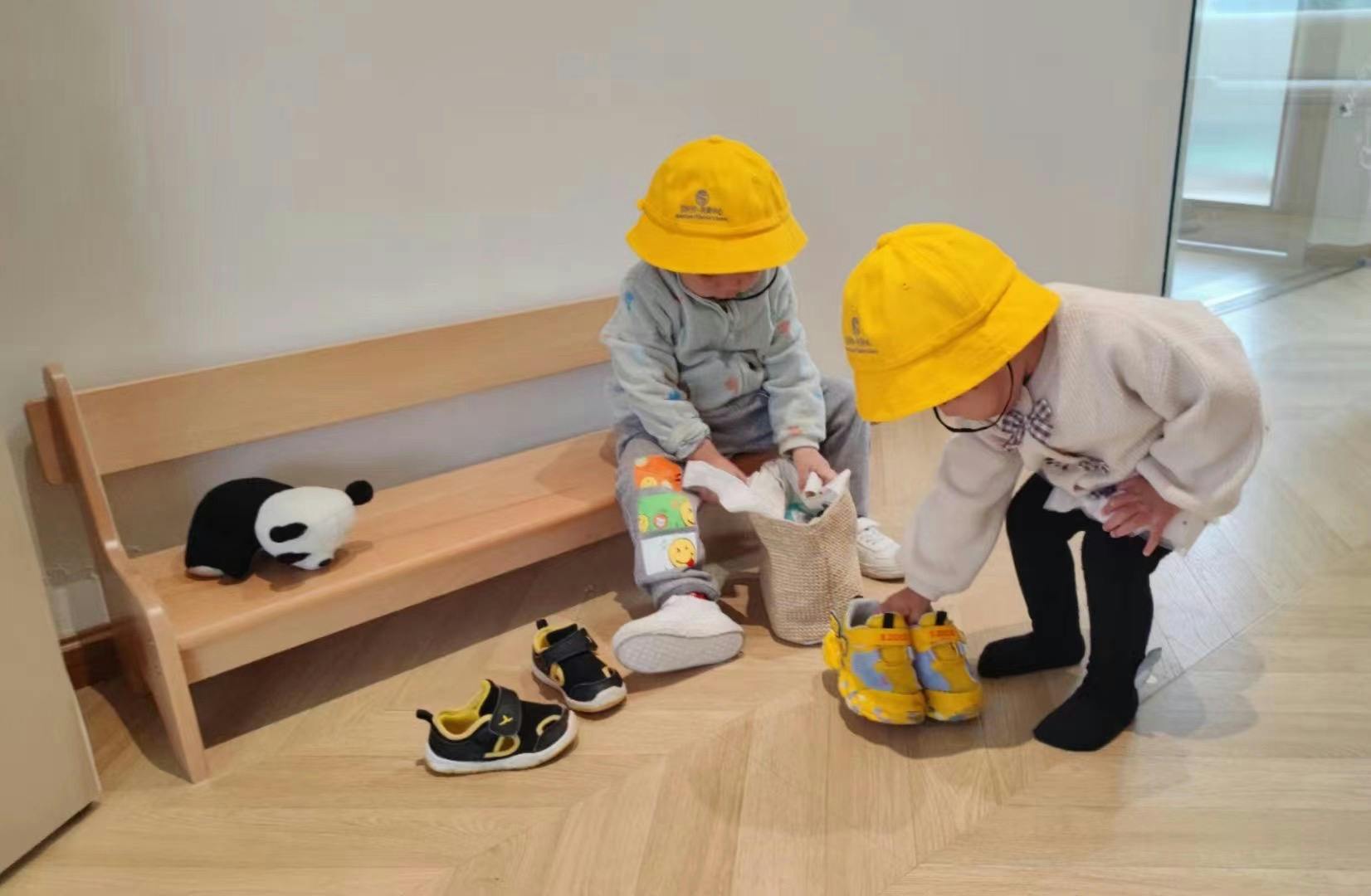 Two children in yellow hats playing with shoes