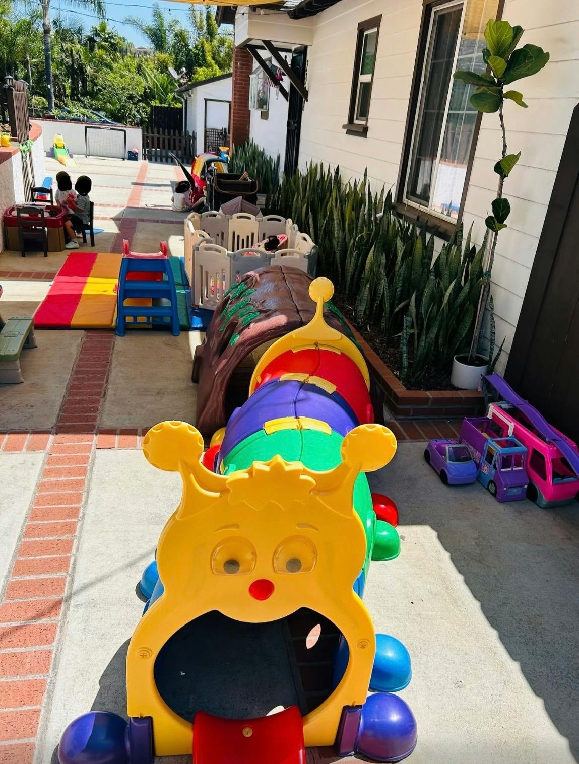 Caterpillar play tunnel and other children's toys on a backyard patio
