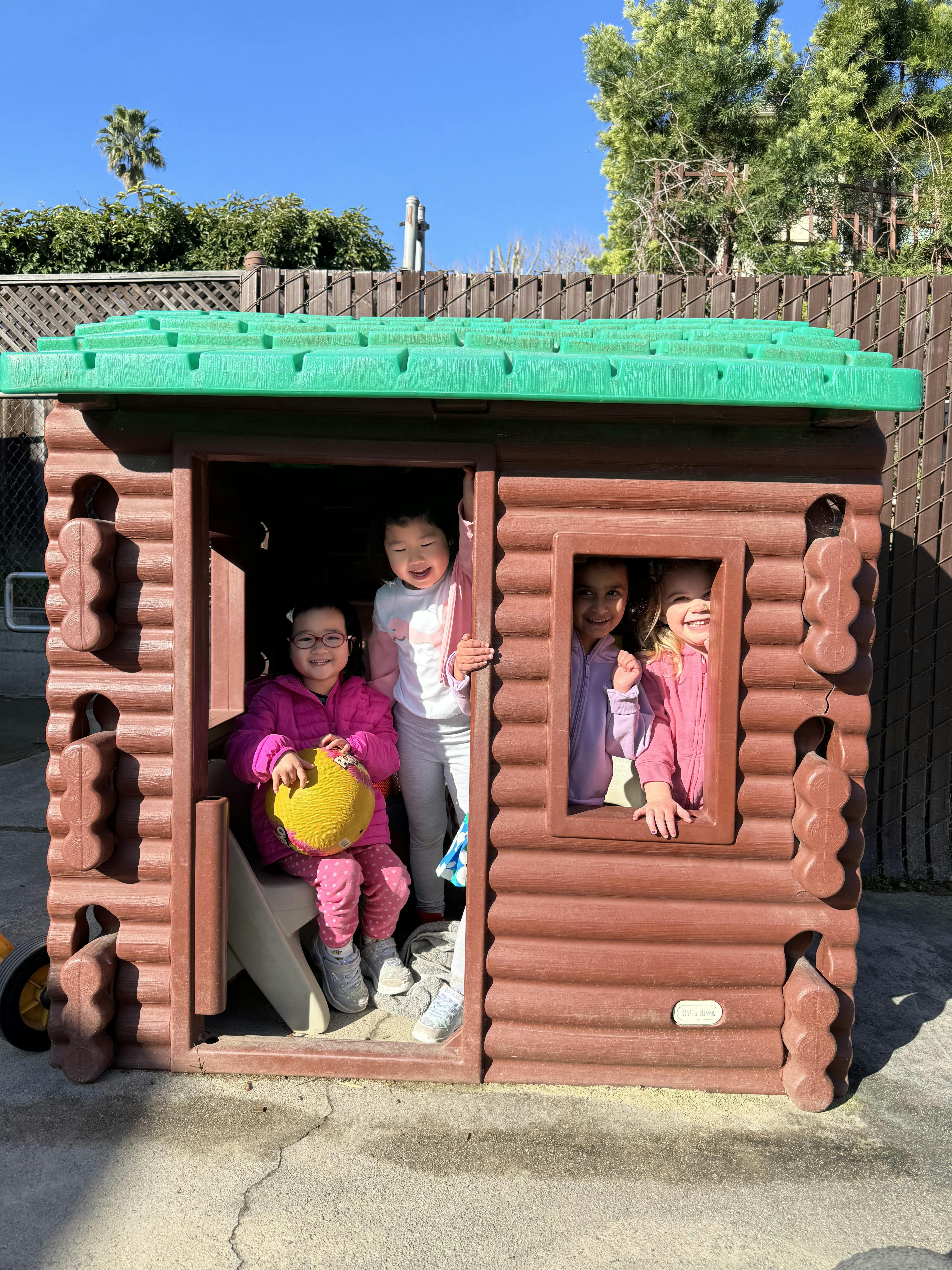 Children playing in a small wooden playhouse