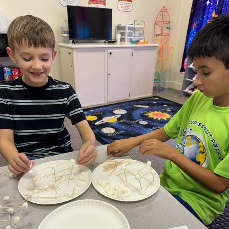 Two children building structures with toothpicks and marshmallows