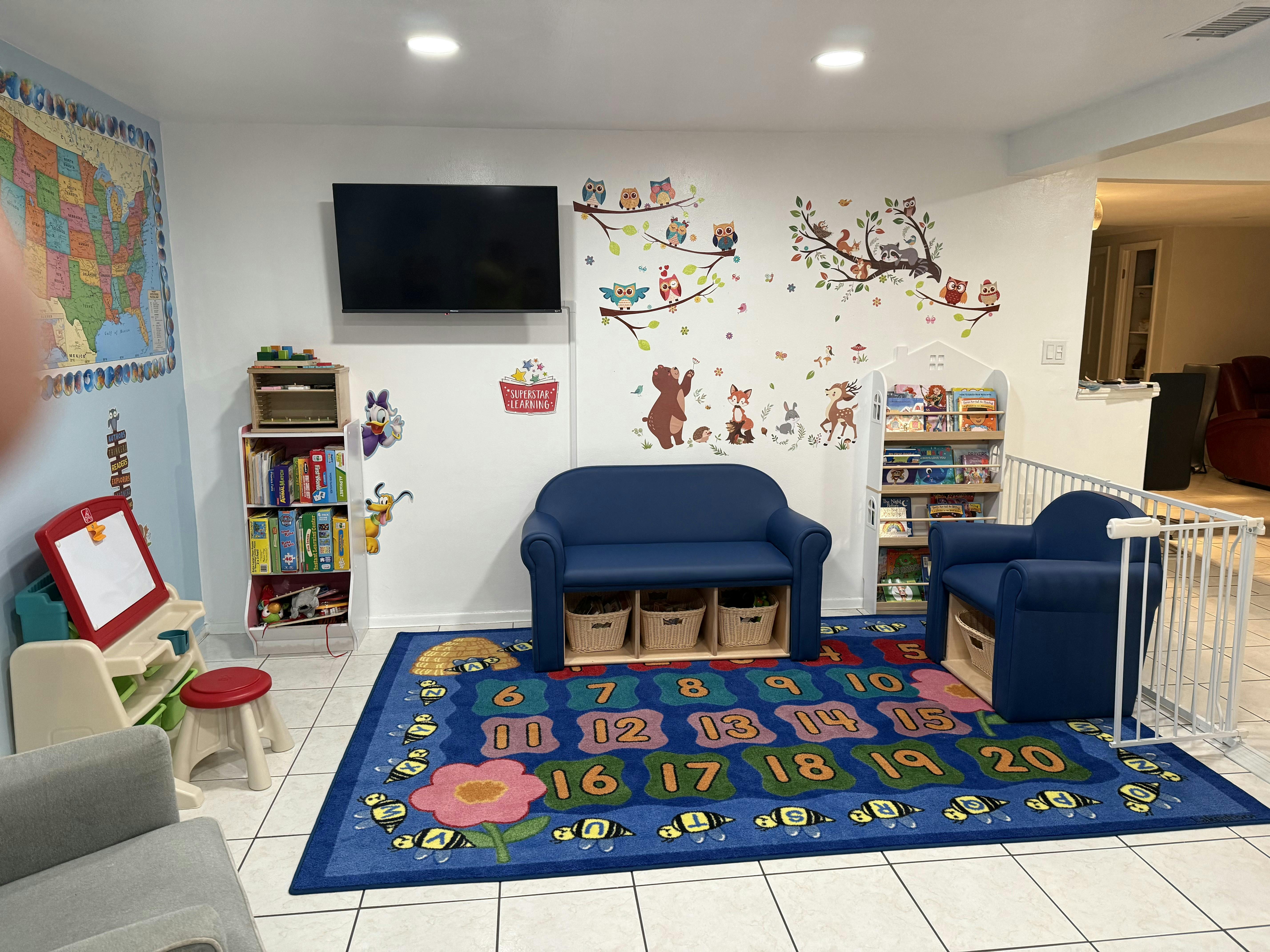 Children's play area with blue couches, a colorful rug, and wall decals