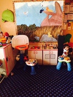 Child playing with toys in a room with a basketball hoop and mural