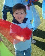 Child holding a red fabric streamer