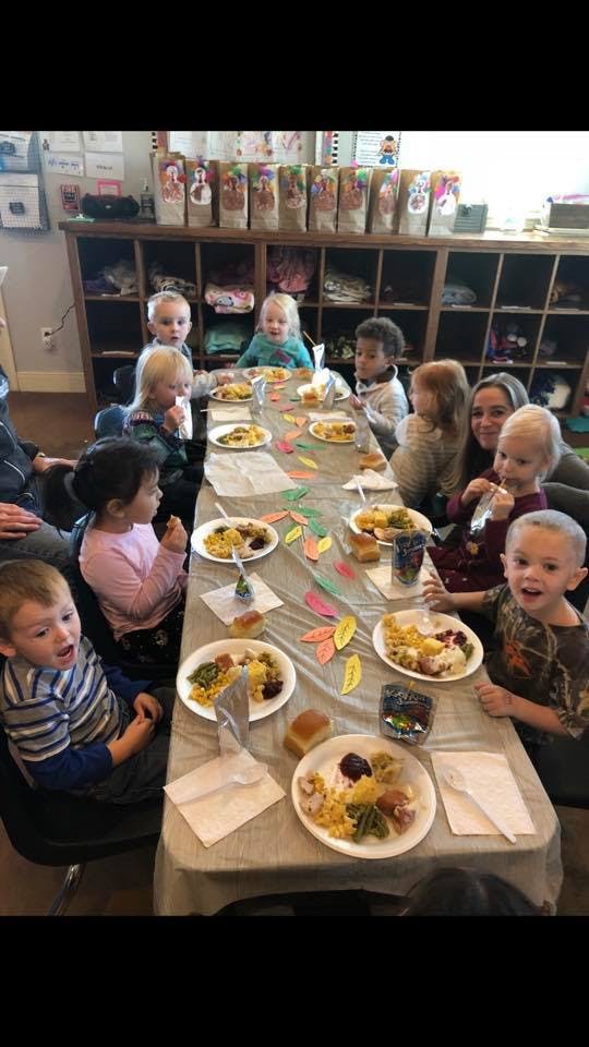 Children and adults sitting around a table with plates of food