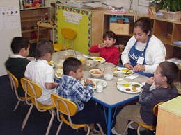 Adult and children eating at a table in a classroom