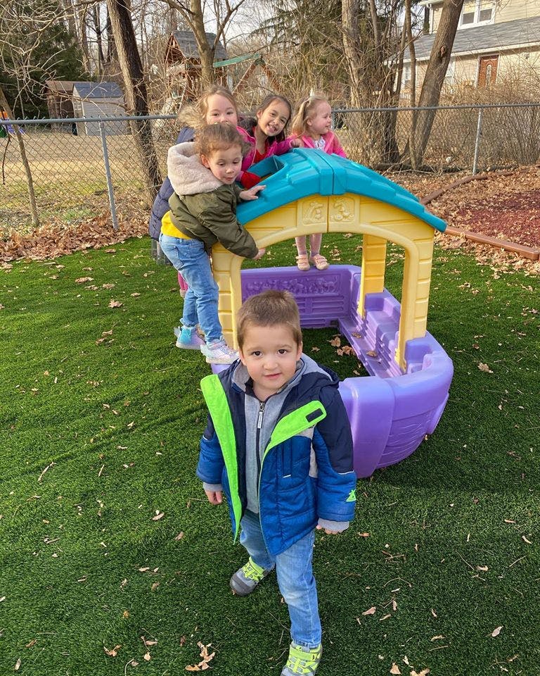 Children playing on a small plastic slide and play structure
