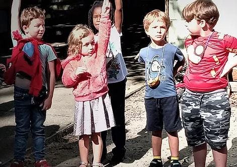 Group of children standing, one child raising a hand