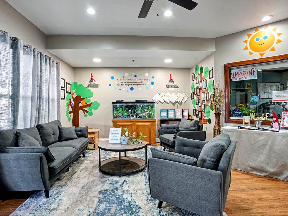 Lobby area with gray couches and armchairs, aquarium, and wall murals